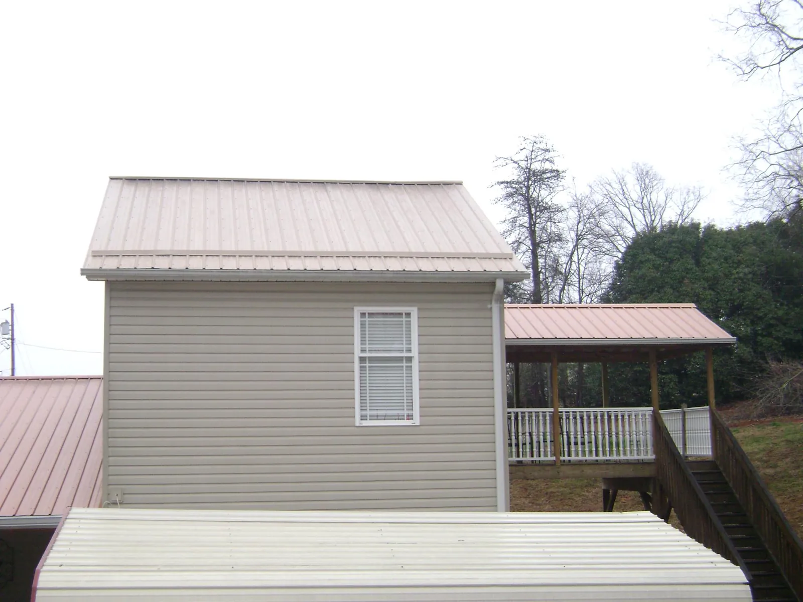 Tan metal roofs on a two story addition and attached porch, from a Roof Replacement job in Bishopville