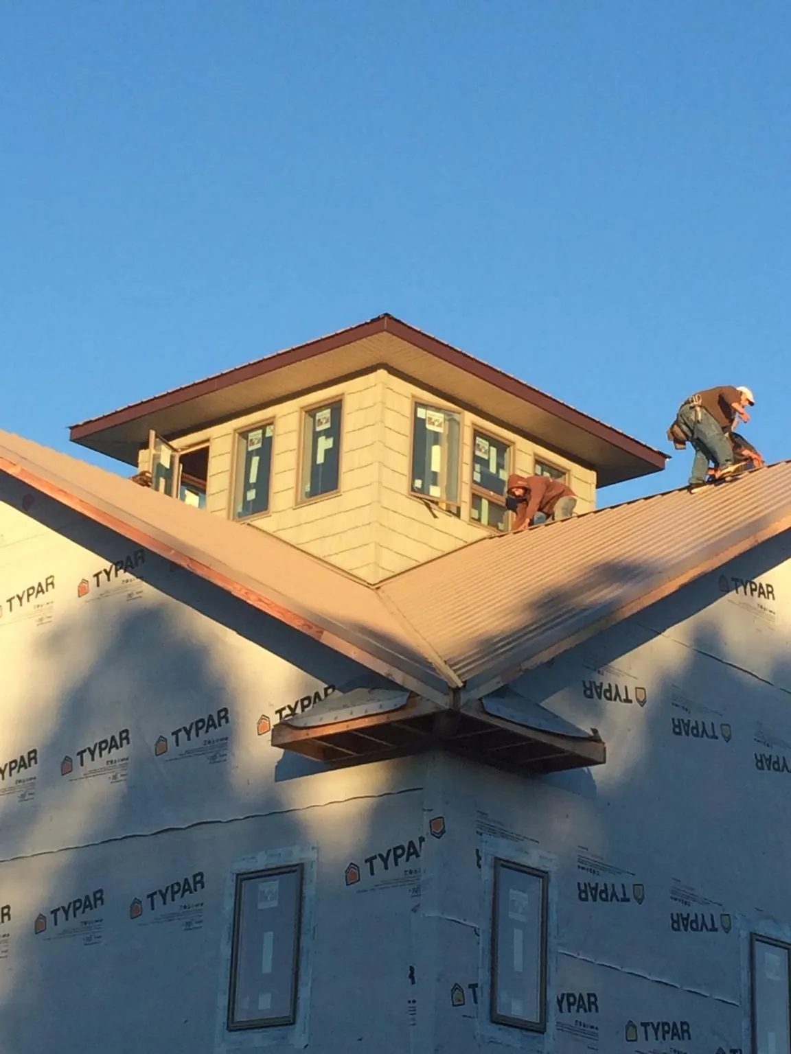 Roofers working around a rooftop cupola on a new metal roof at sunset — Roof Waterproofing in Bishopville by Roofing Brothers